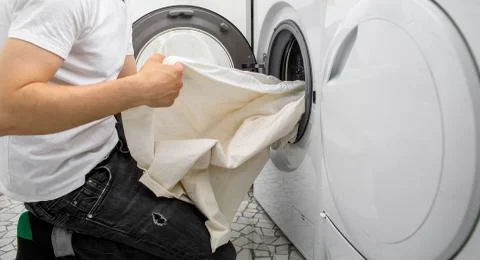 Man puts laundry in an automatic washing machine Photos