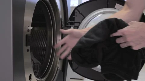 Man puts laundry in the washing machine Stock Footage 202374724