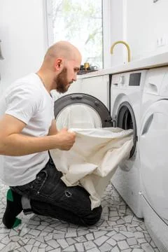 Man puts laundry in a washing machine Stockfoto's