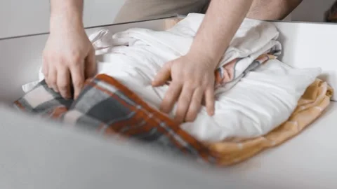  Man puts linens into under the bed storage. Bedroom organization. Small space c Stock Footage 305314719