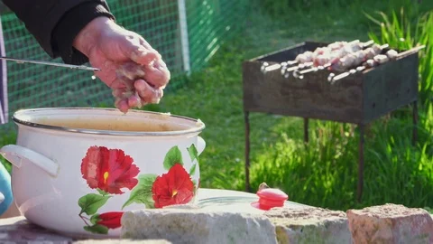 A man puts marinated pieces of meat on a skewer and kebab on the background Stock Footage 106337764