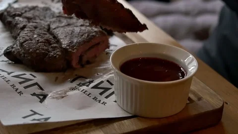 Man puts meat on a fork in a sauce Video stock 77412979