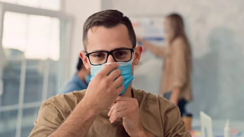Man Puts on Medical Mask in Creative Office. Medical Protection at Work. Man Stock Footage 217845178