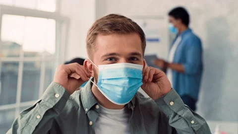 Man Puts on Medical Mask in Creative Office. Medical Protection at Work. Man Stock Footage 217846720