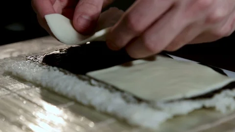 A man puts melted cheese for roll on a nori sheet of algae with rice.Close-up 스톡 동영상 87012277
