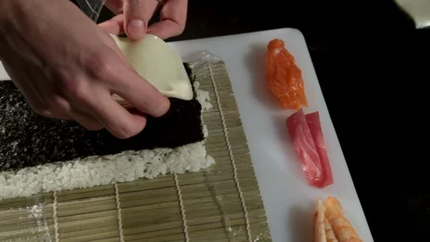 A man puts melted cheese for sushi on a nori sheet of algae with rice.Closeup 스톡 동영상 87012294