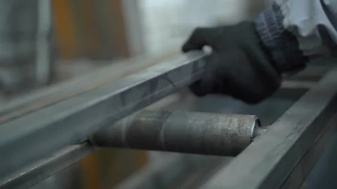 A man puts a metal pipe on a rail, prepares it for cutting. Stock Footage 157280354