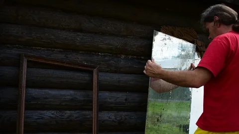 Man puts a mirror to the log wall Stock Footage 117112109