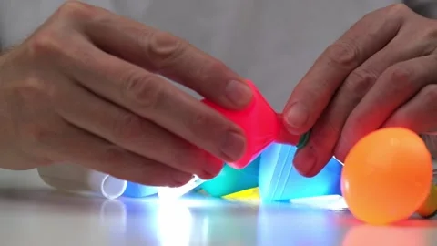 Man puts multicolored plastic lampshades on cartridges with glowing bulbs. Stock-Footage 199201645
