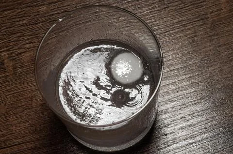 A man puts one effervescent tablet in a glass that dissolves in water Stock Photos