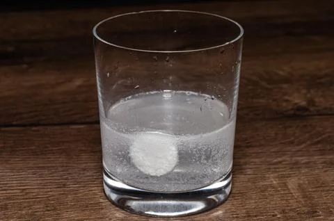 A man puts one effervescent tablet in a glass that dissolves in water Stock Photos
