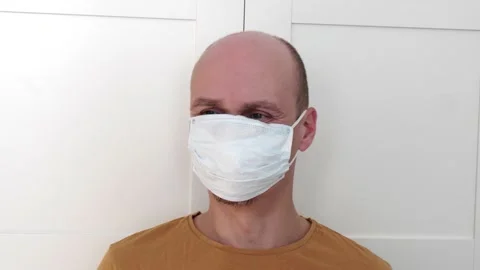 A man puts on one, the second protective hygienic disposable medical mask Stock Footage 152342913