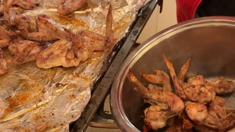 A man puts oven-cooked chicken wings into a pot Stock Footage 301914860