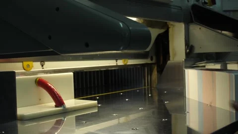 Man puts pack of flyers in automated cutting machine equipment in print house. Stock Footage 262545373