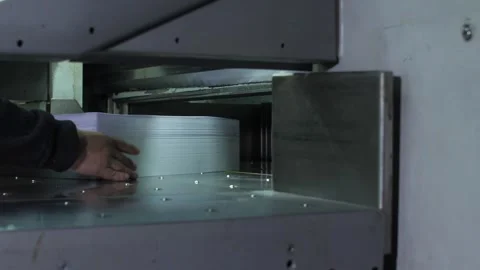 Man puts pack of flyers in automated cutting machine equipment in print house. Video stock 262545489