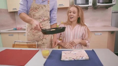 A man puts a pan with scrambled eggs in front of his wife Stock Footage 142999745