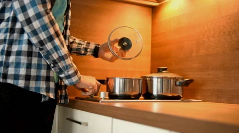 Man puts a pan on a stove Stock Footage 47856532