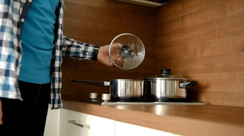Man puts a pan on a stove Stock Footage 47856572