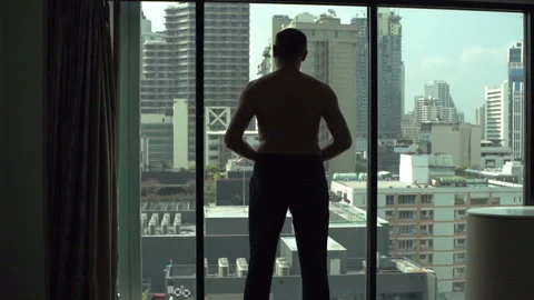 Man puts pants on while standing in front of the window, slow motion Stock Footage 88543101