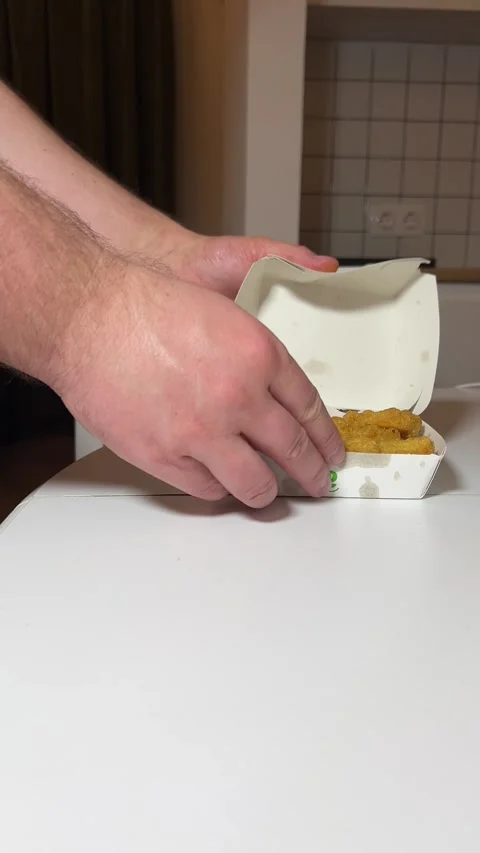 Man puts paper box with yellow McDonald's logo on white wooden table Stock Footage 304770233