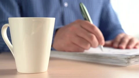 Man Puts A Pen On A Stack Of Papers And Takes A Mug Of Drink. Stock Footage 166995770