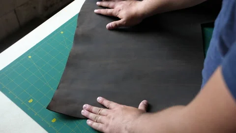 A man puts a piece of leather on the table. Top view as a man unfolds and Stock Footage 198494664