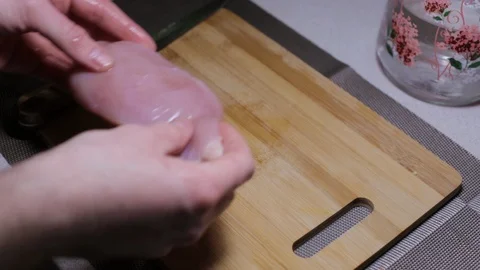 Man puts a piece of raw chicken meat on a cutting board, cooking at home Stock Footage 125907972