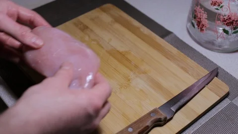 Man puts a piece of raw chicken meat on a cutting board, cooking at home Stock Footage 125907981