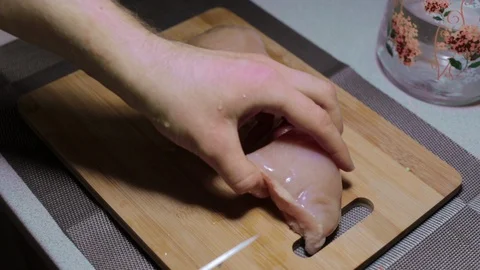 Man puts a piece of raw chicken meat on a cutting board, cooking at home Stock Footage 127650522