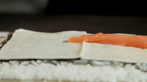 Man puts a piece of salmon on the melted cheese that lies on the nori sheet. 스톡 동영상 87012306