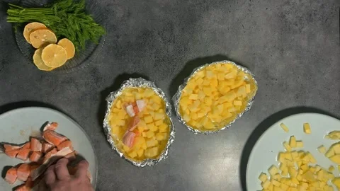 Man puts pieces of red fish, raw salmon, trout on sliced ​​potatoes in foil Stock Footage 289033985