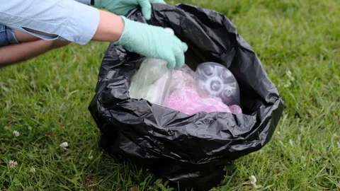 A man puts plastic bottles and other garbage into a bag Stock Footage 113684673