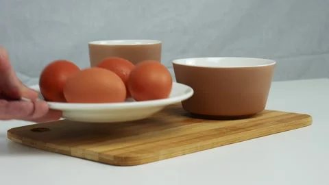 A man puts a plate with eggs on the table. White table, mug, bowl Stock Footage 102129825