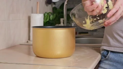 The man puts potatoes cut into thin slices into bowl of slow cooker. Fast Stock Footage 229928337