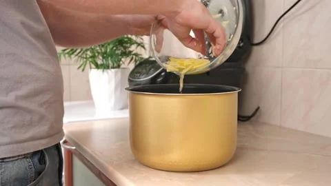 The man puts potatoes cut into thin slices into bowl of slow cooker. Fast Stock Footage 230721349