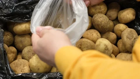 A man puts potatoes in plastic bag in a supermarket close-up. Stock Footage 169489813