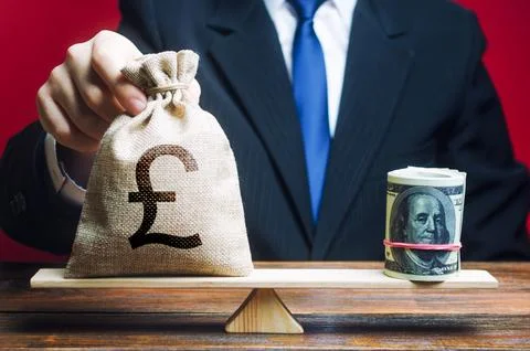 A man puts a pound sterling GBP money bag on the scales opposite to the dol.. Stock Photos