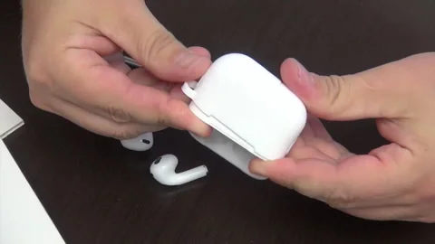 A man puts on a protective silicone cover on a case with wireless headphones. Stock Footage 277114293