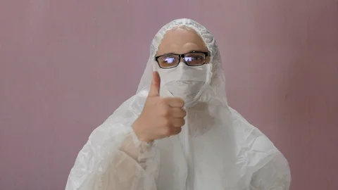 Man puts protective suit and mask against covid-19 and looks at camera. Stock Footage 127384318