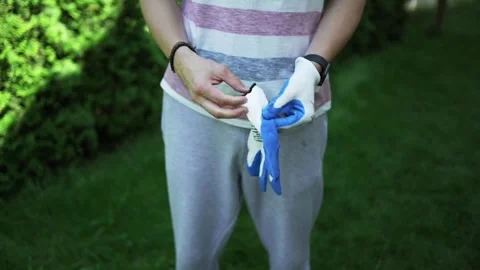 Man puts protective work gloves on his hands, prepare to garden work, work Stock Footage 246661903