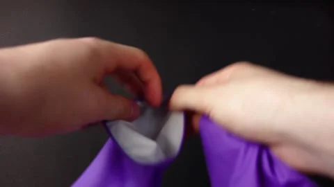 A man puts on purple gloves on a dark background Video stock 130664845