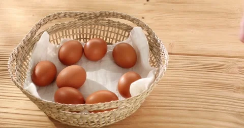 Man puts raw Eggs in a basket on a wooden background. Close-up. High angle view. Stock Footage 242854999