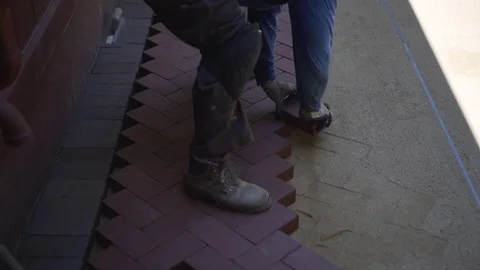 Man puts red brick pavers into a herringbone pattern on a foundation of sand. Stock Footage 81559337