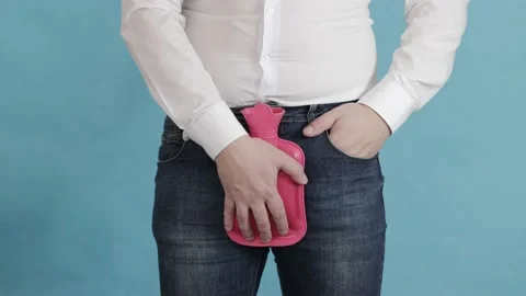A man puts a red heating pad with hot water in the groin area. The concept of Stock Footage 199075955