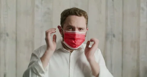 Man puts on a red medical mask, and shows the viewer wearing medical masks Stock Footage 200423456