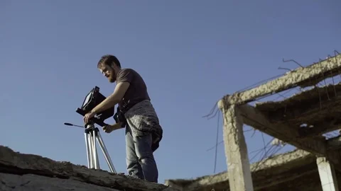Man puts a retro camera near a ruined building Stock Footage 72102165