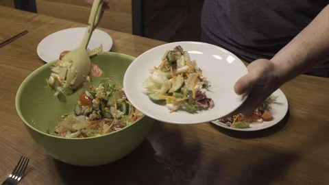 Man puts salad in a plate on the background of a plate with salad Stock Footage 101662697