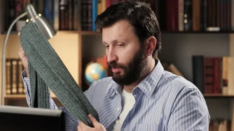 Man puts on scarf. Man at workplace in office or apartment works on laptop, he Stock Footage 139284894