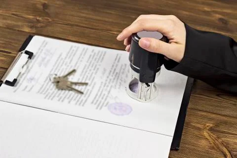 A man puts a seal on documents when buying an apartment, the keys to the Photos