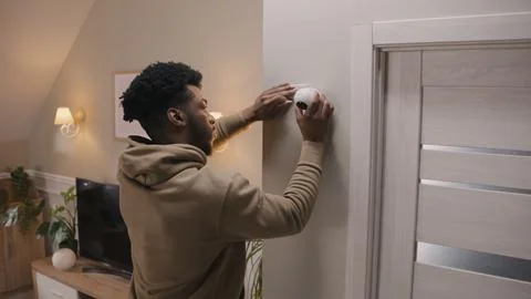 Man puts security camera on wall fastening Stock Photos